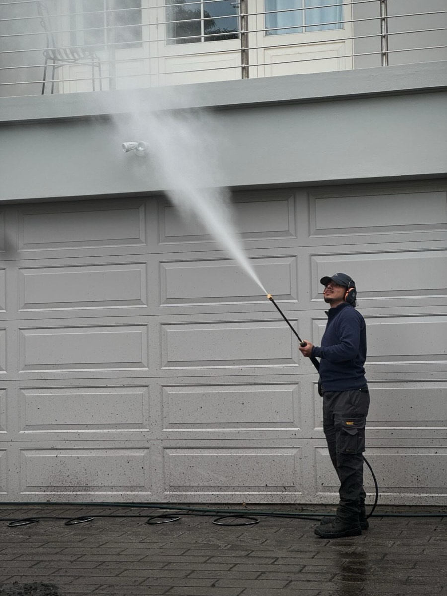 The Ardor Clean founder pressure-washing the upper exterior of a Sydney home